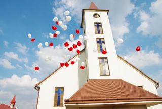 balony z helem na tle kościoła, atrakcje na ślub, wypuszczenie balonów w niebo